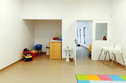 Sala da creche com zona de higiene e cadeira de refeição
