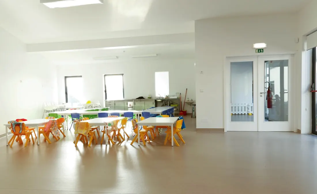 Sala ampla com mesas e cadeiras laranja junto às janelas